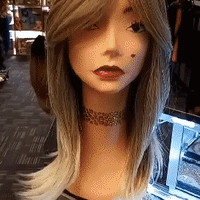 White Mannequin head with a tattooed necklaceon pink store counter modeling Empire Blonde Glueless Synthetic shoulder length Hair Wigs for $79 at Optimismic Wigs and Gifts Shop in St Paul Minnesota. 